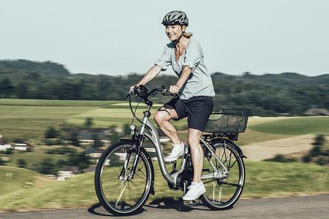 Frau auf dem E-Bike mit Velo-Helm